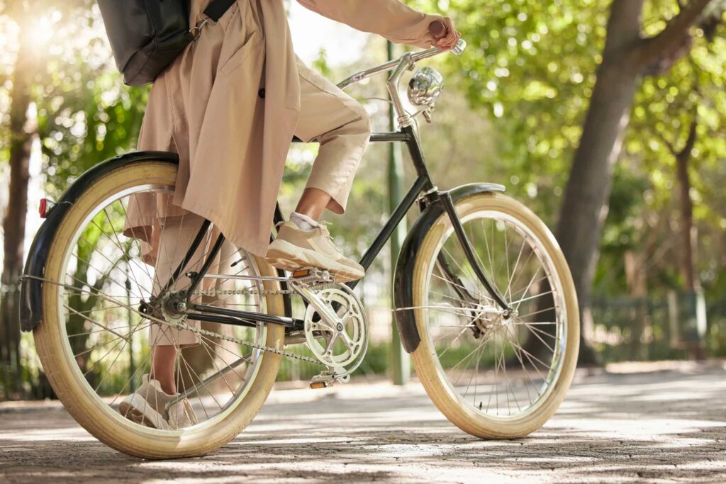 Frau fährt auf einem Fahrrad, umgeben von Bäumen bei strahlendem Sonnenschein.